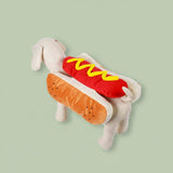 Medium dog sitting comfortably while wearing a funny hot dog pet apparel
